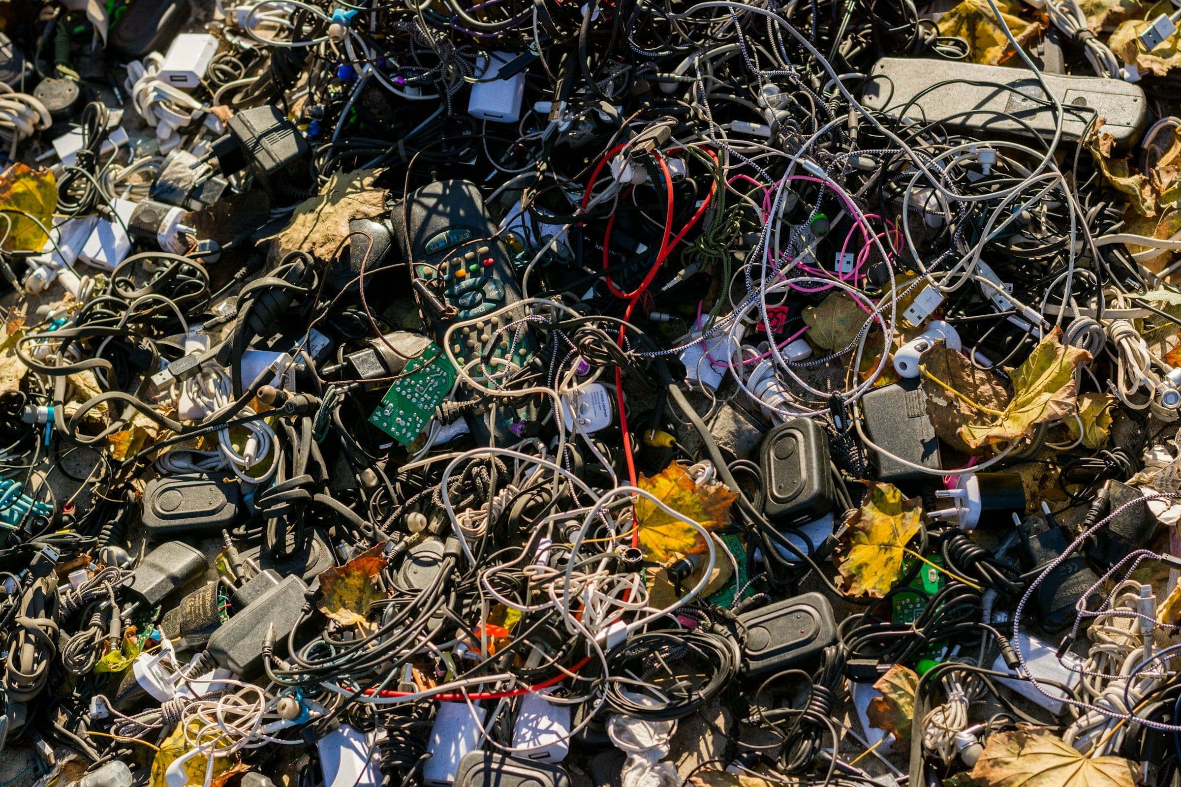 Waste from electronic devices, including old smartphones, laptops and cables, collected for recycling to reduce harmful substances and recover valuable materials.